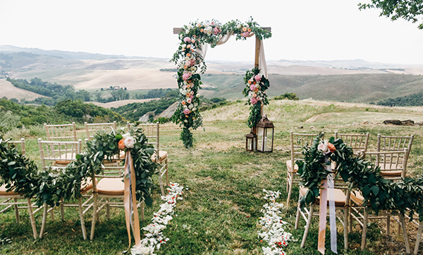 wedding ceremony setup with floral arch and decorated chairs in scenic landscape two wedding chairs adorned with floral arrangements
